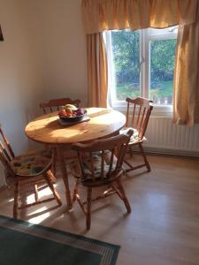 a wooden table with chairs and a bowl of fruit on it at The Homestead, Cliff-en-Howe Rd, Pott Row, Kings Lynn in Grimston