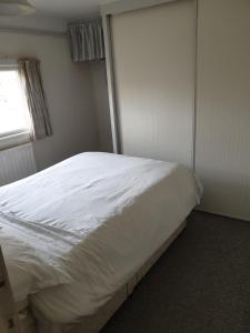 a white bed in a room with a window at The Homestead, Cliff-en-Howe Rd, Pott Row, Kings Lynn in Grimston