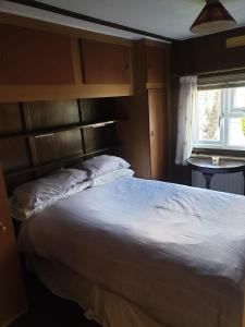 a bedroom with a white bed with a wooden headboard at The Homestead, Cliff-en-Howe Rd, Pott Row, Kings Lynn in Grimston
