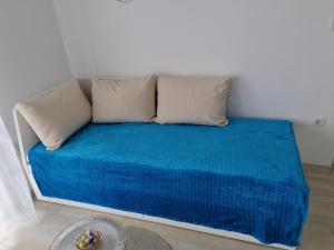 a couch with two pillows and a blue blanket at Crystal Blue Apartments in Nea Kalikratia