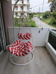 a red and white chair sitting on a balcony at Crystal Blue Apartments in Nea Kalikratia