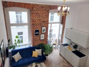 a living room with a blue couch and a brick wall at Narutowicza 41 Apartments in Łódź