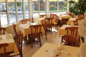 una sala da pranzo con tavoli, sedie e finestre di Hotel Selliner Hof a Ostseebad Sellin