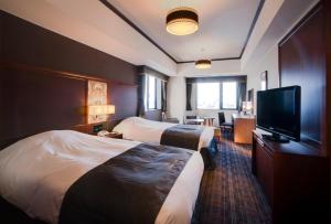 a hotel room with two beds and a flat screen tv at Hotel Monterey Grasmere Osaka in Osaka