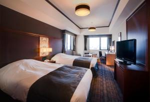 a hotel room with two beds and a television at Hotel Monterey Grasmere Osaka in Osaka