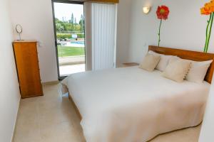 ein Schlafzimmer mit einem großen weißen Bett und einem Fenster in der Unterkunft Sunny villa facing the swimming pool in Fontainhas