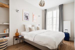 Un dormitorio con una gran cama blanca y una ventana en Edgar Suites Champs Elysées - Boétie, en París