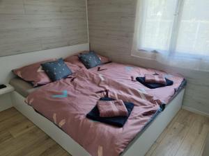 a bed in a bedroom with pink sheets and pillows at Levendula Jakuzzis Vendégház in Gárdony