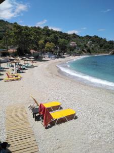 Una playa con sillas y sombrillas y el océano. en Kamari Beach guest house, en Keramídhion