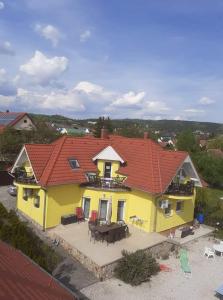 a yellow house with a red roof and a patio at Csikós Apartman in Gyenesdiás