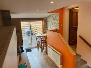 a kitchen with an orange wall and a table and chairs at LE PETIT NID in Hunawihr