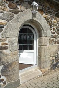 uma janela arqueada numa parede de pedra com uma luz em LES BRUYERES em Scrignac