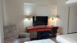 ブラジリアにあるFlat Particular Hotel Kubitschekのデスク、テレビ、椅子が備わる客室です。