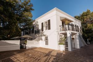Dieses weiße Haus verfügt über eine Veranda und einen Balkon. in der Unterkunft Maison Chablis Guest House in Franschhoek