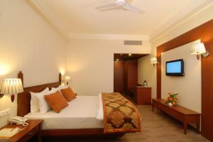 A bed or beds in a room at Chanakya Bnr Hotel