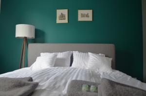 1 dormitorio con cama blanca y pared verde en Lighter Apartment, en Gdansk