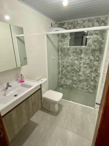 a bathroom with a shower and a toilet and a sink at Apartamento em chácara próximo as praias com piscina e quiosque com internet in São Francisco do Sul