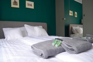 Una cama con toallas y una pared verde. en Lighter Apartment, en Gdansk