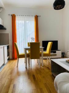 a dining room with a table and yellow chairs at Apartment DORA in Cetinje