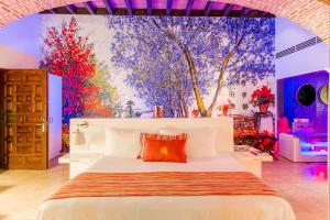 a bedroom with a large white bed with a painting on the wall at Anticavilla Hotel Restaurante & Spa in Cuernavaca