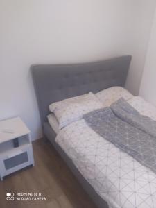 a bed with a gray headboard and a night stand at Modern Apartman in Szeged