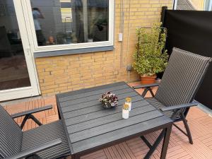 einen Holztisch und zwei Stühle auf einer Terrasse in der Unterkunft AgerBro in Broager