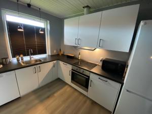 a kitchen with white cabinets and a sink and a refrigerator at AgerBro in Broager