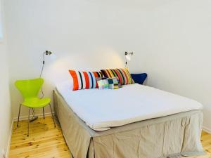 a bed in a room with a green chair at Stockholm archipelago with pool, boat and bikes in Djurhamn