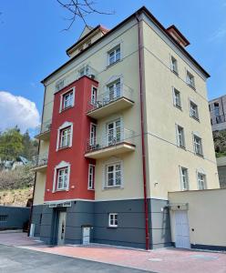 um edifício vermelho e branco ao lado de uma rua em Apartmány Tatra em Jáchymov