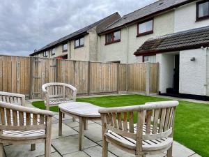 a backyard with two benches and a table and a fence at Feel at home while you roam in Caol