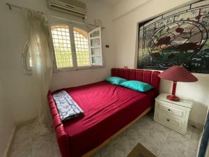 a red bed in a room with a lamp and a window at Four Bedroom Chalet at Marina 4 Private Pool and Garden in El Alamein