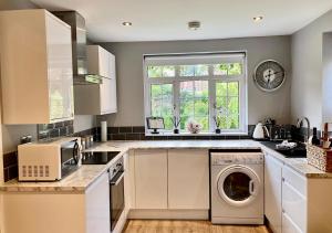a kitchen with a washing machine and a window at The Lodge Chester - luxury apartment for two, with free parking! in Hough Green