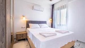 a bedroom with a white bed with two towels on it at Golden Rose Suit pension in Kaş