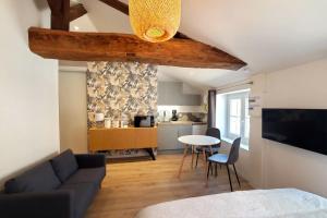 a living room with a couch and a table at L'IDYLLE - Studio Cocooning avec Jacuzzi in Mâcon