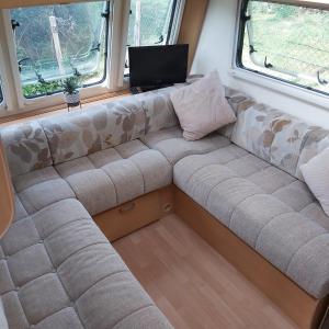 ein Sofa in der Mitte eines Zimmers mit zwei Fenstern in der Unterkunft Caravane Les Fontenelles in Saligny-sur-Roudon