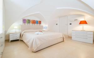 ein weißes Schlafzimmer mit einem weißen Bett und zwei Lampen in der Unterkunft Le Pativite Luxury Apartments by HDSalento in Santa Maria di Leuca