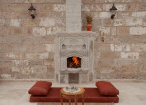 a stone fireplace in a room with a table and chairs at Narcissos Cave Hotel in Urgup