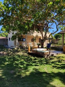 una casa con un árbol, una mesa y un columpio en O Caramuru Hostel - Cumuruxatiba, en Cumuruxatiba