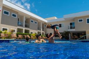 a group of children playing in a swimming pool at Orquídeas Praia Hotel in Porto Seguro