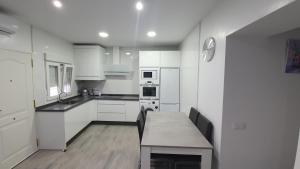 a kitchen with white cabinets and a table with chairs at Casa Las Marismas in Barbate