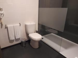 a bathroom with a white toilet and a bath tub at Leiria Village casa bungalow in Leiria