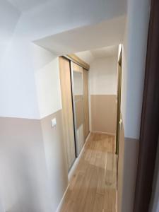 een lege hal met een deur en een houten vloer bij Maison chaleureuse avec netflix et ps5 in Valenciennes