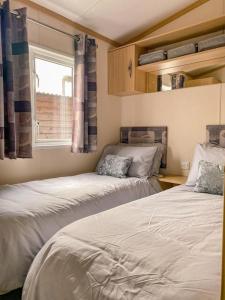 two beds in a small room with a window at Ruddingwood Lodge in Tuxford