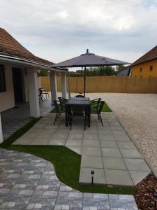 a patio with a table and an umbrella at Csengő Vendégház in Kiskőrös