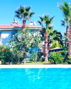 une maison avec des palmiers et une piscine dans l'établissement Уютная квартира рядом с морем, à Kemer