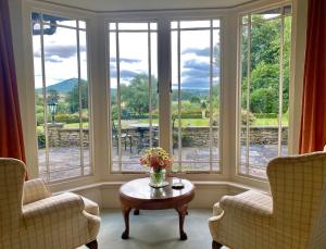 a room with two chairs and a table and windows at Old Hall Cressage in Shrewsbury