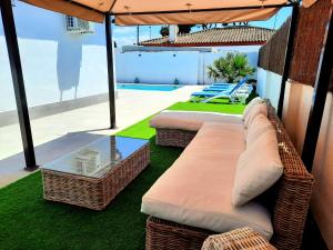 a balcony with two wicker chairs and an umbrella at VILLA SANCTI PETRI in Chiclana de la Frontera