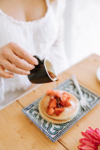 a person pouring syrup onto a plate of fruit at Dimora Anderì in Polignano a Mare