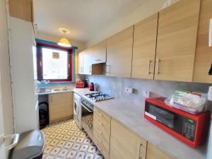 a kitchen with a red microwave and a stove at 3 Bedroom Aprtmt at Sensational Stay Serviced Accommodation Aberdeen- Froghall Avenue in Aberdeen