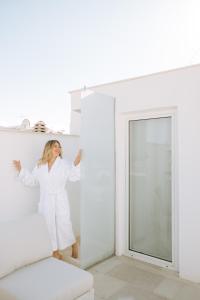 a woman in a white robe standing in a white room at Dimora Anderì in Polignano a Mare